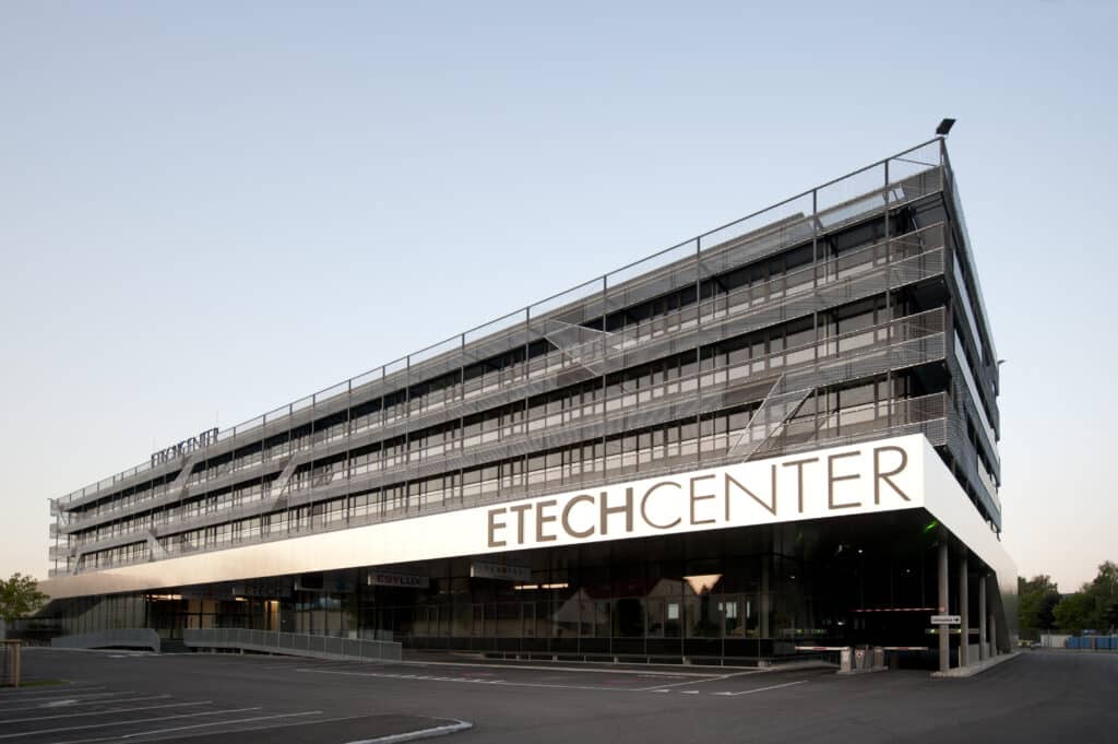 ETECHCENTER Linz – modernes Bürogebäude mit Glasfassade und markanter Beschriftung auf dem Parkplatz