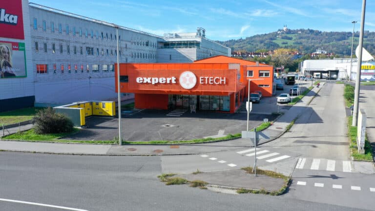 Außenansicht des expert ETECH Elektrofachhandels in Graz aus der Vogelperspektive, orangefarbene Fassade mit Logo
