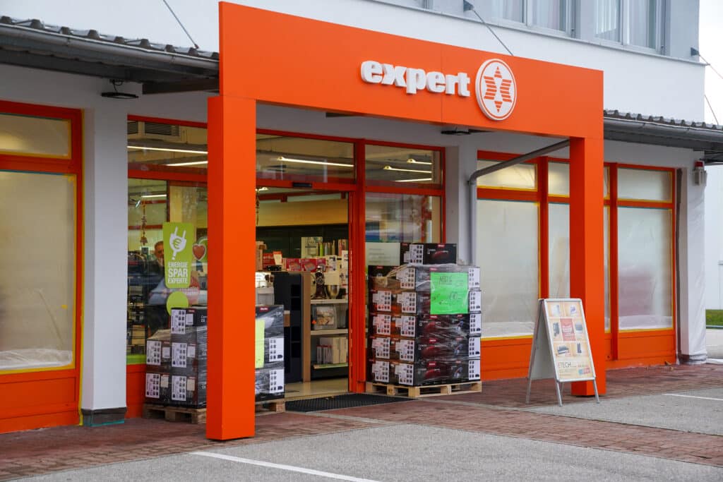 Expert-Fachhandelsgeschäft von ETECH Gmunden mit orangefarbenem Eingangsbereich und ausgestellten Miele-Produkten