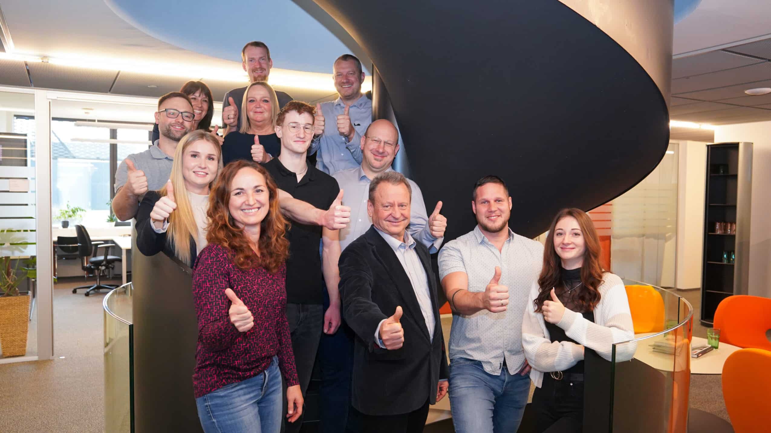 ETECH-Team mit Daumen hoch in der modernen Zentrale von ETECH