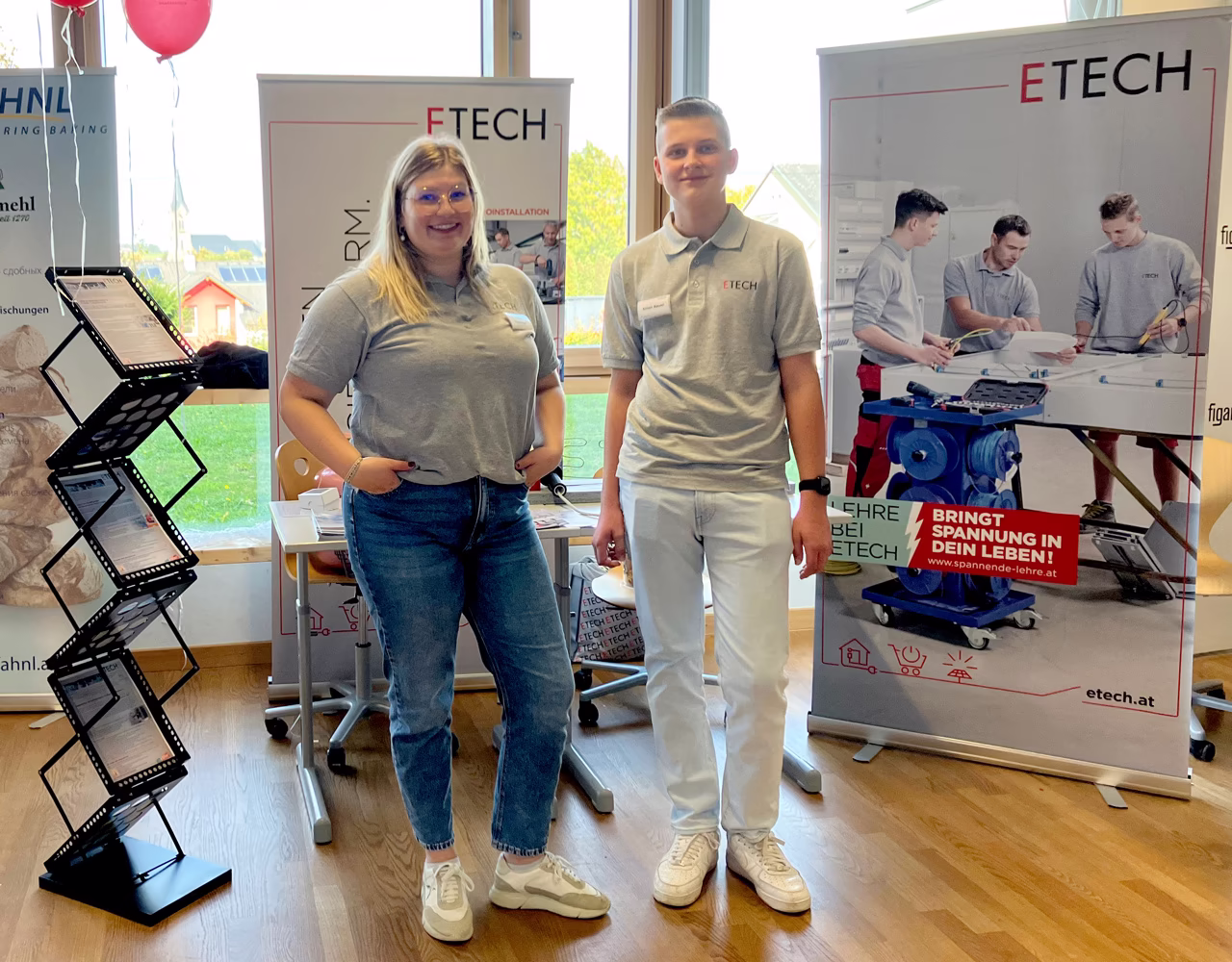 Zwei ETECH-Mitarbeiter in grauen Polo-Shirts stehen vor ETECH-Rollup-Bannern auf der Bildungsmesse PTS Pregarten.