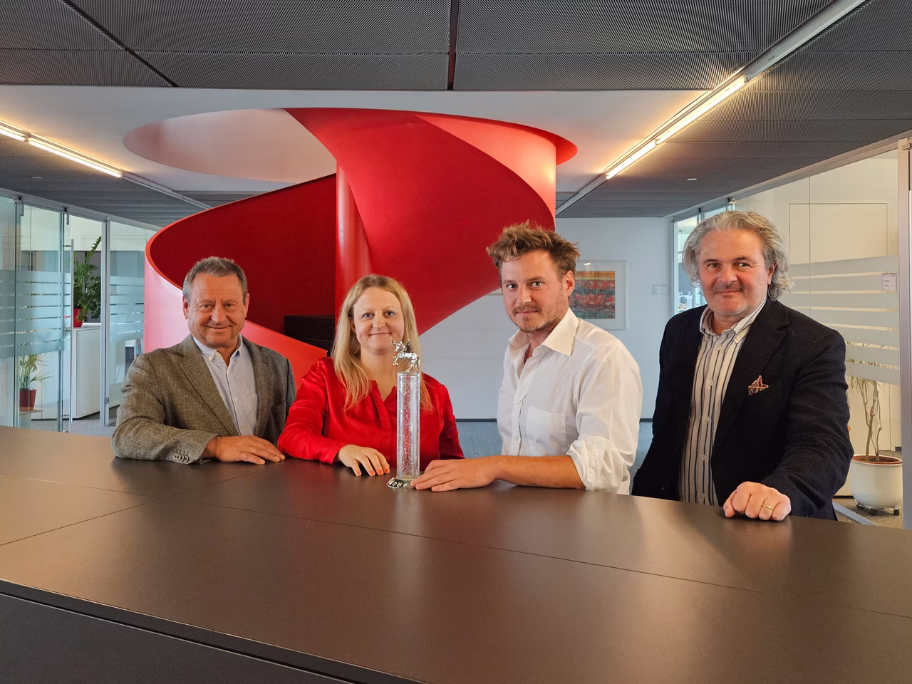 ETECH-Team mit Pegasus-Award auf Platz 2: Vier Personen posieren stolz mit einer Glastrophäe vor roter Wendeltreppe.
