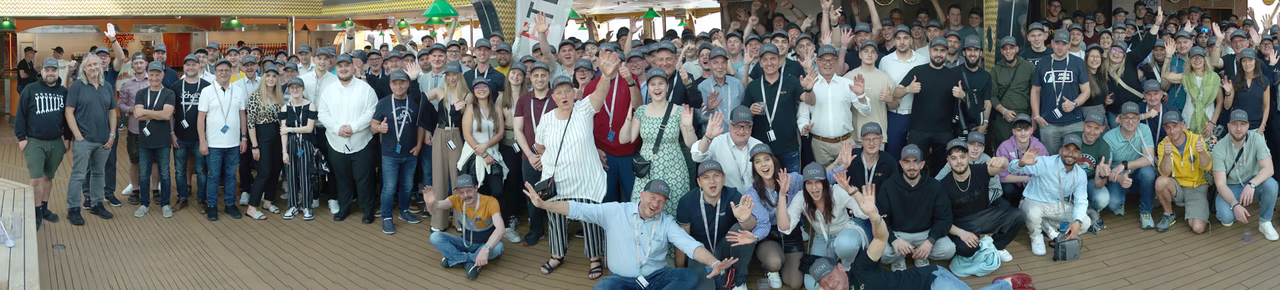 Große Gruppe von ETECH-Mitarbeitern und Lehrlingen beim gemeinsamen Gruppenfoto auf einem Kreuzfahrtschiff, viele mit grauen Caps.