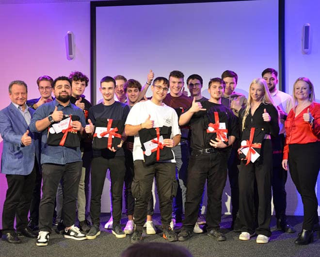 Gruppe junger ETECH-Lehrlinge bei der Lehrabschlussfeier, stolz mit Geschenken und erhobenen Daumen auf der Bühne