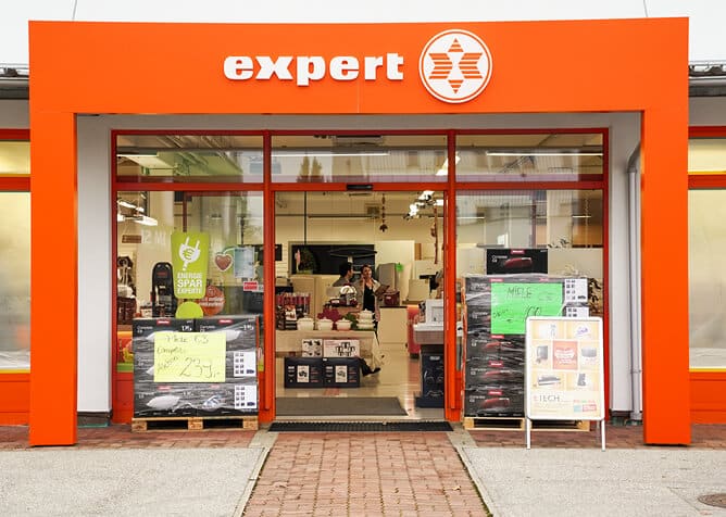 Außenansicht des ETECH-Standorts Gmunden im Expert-Fachmarkt mit orangefarbener Fassade und Schaufenster